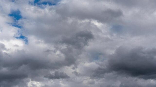 Time lapse of black clouds. The sky is cloudy and gray with black clouds scattered everywhere. The scene is dark and somewhat gloomy.