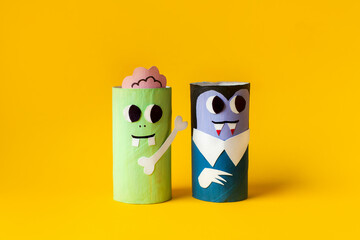 Halloween monsters from toilet paper roll tube, easy DIY handmade decorations idea. Paper toys zombie and vampire on yellow background. Kids creativity, easy eco craft, step by step, place for text