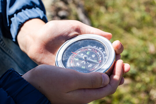 Close-up of a teenage boy sitting outdoors holding a compass, Georgia