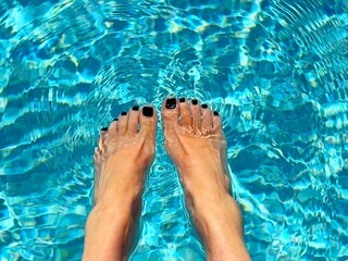 Overhead view of a woman sitting at the edge of a swimming pool dangling her feet in the water