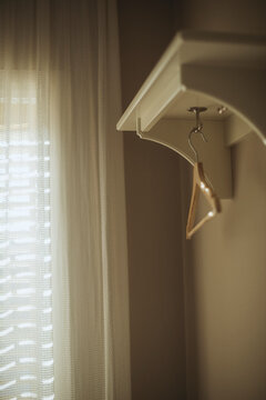 Close-up of a single wooden coathanger hanging under a shelf