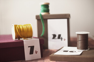 Homemade Gift boxes for a Christmas advent calendar with ribbon spools on a wooden table