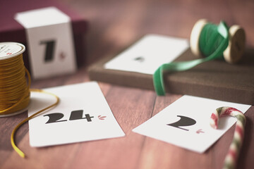 Gift boxes for a homemade Christmas advent calendar with ribbon spools on a wooden table