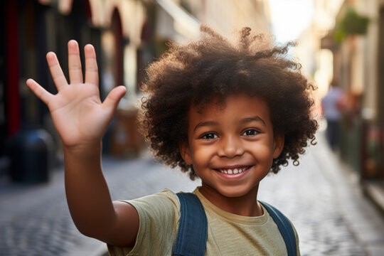 Ni&ntilde;o afroamericano saludando en la calle.