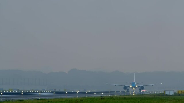 An airplane taking off from a runway with bright lights on a foggy morning, creating a soft, misty atmosphere