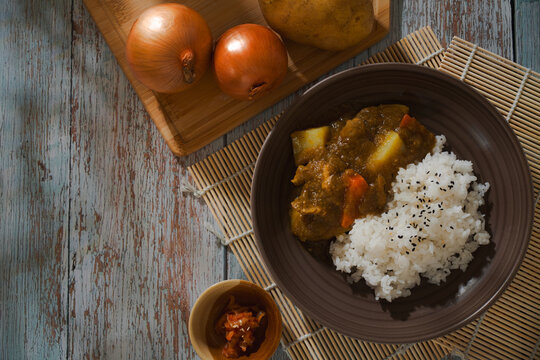 Japanese curry rice served in brown ceramic bowl.