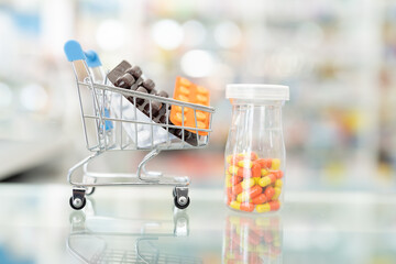 Pharmacy medicine. Medical pills capsule in shopping cart and Medical pills in bottle in pharmacy drugstore with shelves blurred background