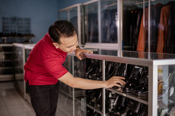asian employee organize leather shoes and putting it into shelves with happy face