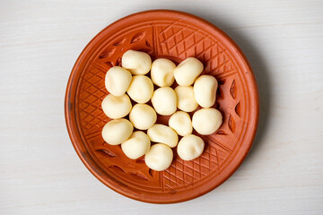 Delicious sweet Sondesh in a clay plate on a light wooden surface. Sandesh is a traditional Bengali...