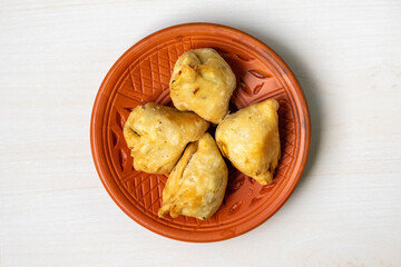 Delicious samosas or singaras on a pottery plate. This is a traditional and popular snack enjoyed in both Bangladesh and India. It is also known as singara, singada, samose, somsa, sambusa, and samuza
