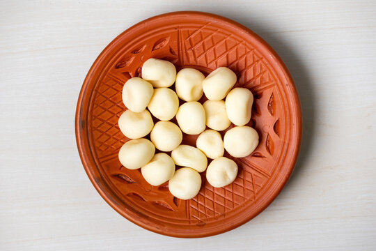 Delicious sweet Sondesh in a clay plate on a light wooden surface. Sandesh is a traditional Bengali dessert made from milk and sugar. Top view.