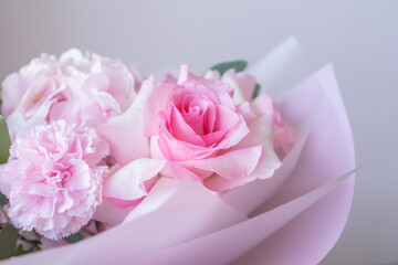 Soft pink floral bouquet with roses and carnations wrapped in pastel paper