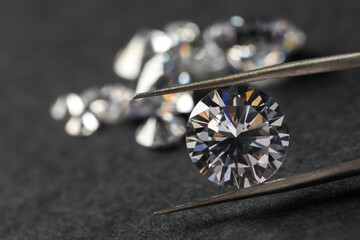 Many beautiful shiny diamonds and tweezers on black table, closeup