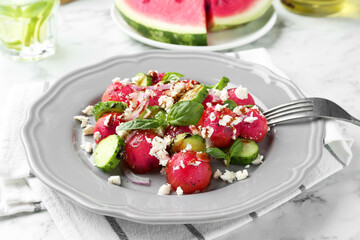 Delicious watermelon salad with feta cheese, vegetables and spices served on white marble table, closeup