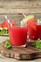 Tasty watermelon drink in glasses, fresh fruit and mint on wooden table, closeup