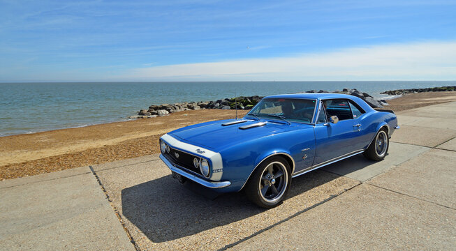 Classic Chevrolet Camero on seafront promenade beach and sea in background