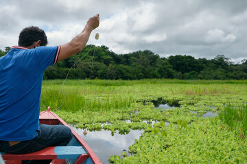 Adult fishing on traditional wooden canoe , Amazon natural reserve
