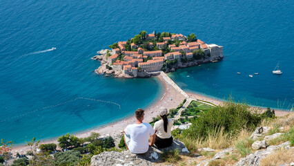 Couple enjoying a breathtaking view of Sveti Stefan Island in Montenegro on a sunny day