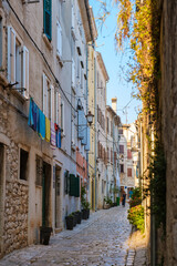Fototapeta premium Charming narrow street in Rovinj, Croatia, adorned with colorful laundry and sunshine