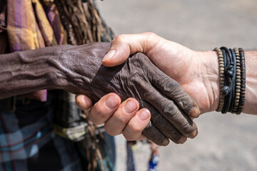 Black and white human hand shake in small village, Danakil depression, Afar region, Ethiopia