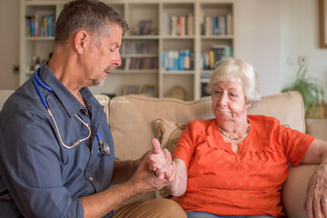 A doctor takes a patients pulse, heartbeat at a routine home appointment. Vital statistics assessment, prevention and healthcare. 