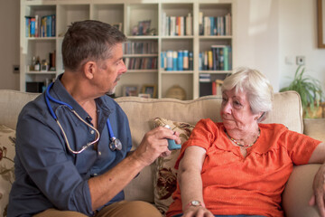 Doctor administering medication to a senior lady at home. Explaining adverse affects of the ...