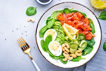 Keto diet salad with salmon, avocado, spinach, eggs and cashew. Gray table background, top view