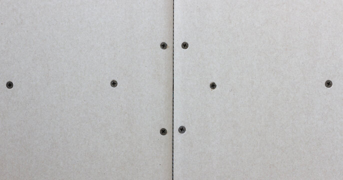 Close up of drywall panels with visible screws, showcasing construction details for interior wall installation.