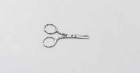Small stainless steel scissors with curved handles on neutral background, ideal for precise cutting...