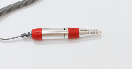 Fototapeta premium Electric nail drill handpiece with red accents on white background, used for professional manicure and pedicure.