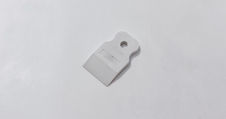 Plastic tool blade withhole, marked 40 MM, lying onlight surface.