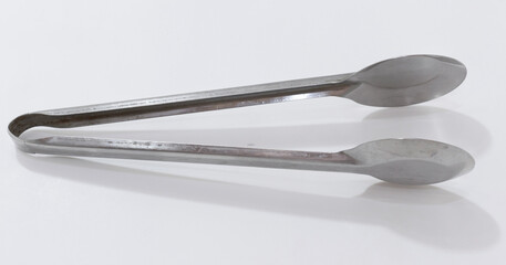 Vintage metal tongs with spoon like ends, suitable for handling small items or delicate tasks.