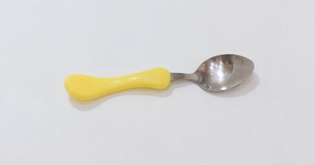 Bright yellow handled spoon on white background, ideal for kitchen and dining related visuals.