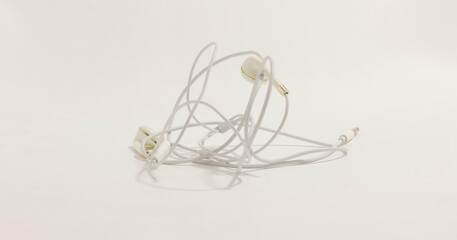 Tangled white earphones on neutral background, symbolizing disorder and frustration in everyday life.