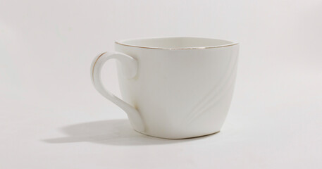 Minimalist white ceramic cup with sleek handle, perfect for coffee or tea, placed against plain background.