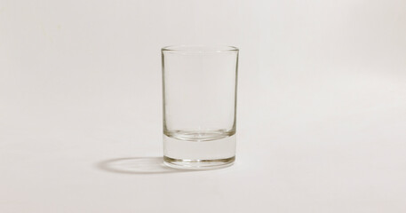 Clear glass shot glass on white background with subtle shadows, perfect for minimalist product presentations.