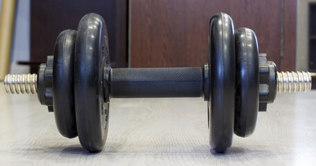 A close up of single adjustable dumbbell resting on wooden floor, ideal for fitness or home gym themes.