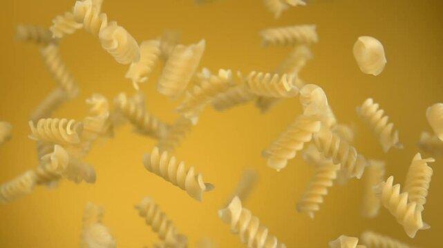Dry pasta fusili bouncing up on a yellow background in slow motion