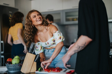 A joyful group of friends shares laughter while cooking together in a modern kitchen. The atmosphere is warm and vibrant, emphasizing friendship and happiness through a shared culinary experience.