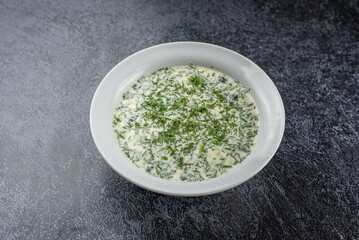 A white bowl of soup with parsley on top