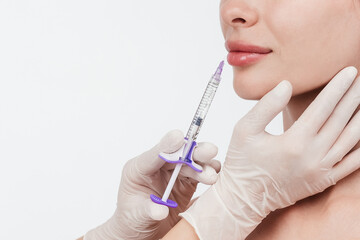 Woman while procedure lip augmentation at cosmetology clinic with beautician. Filler injection for...