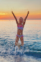 Child's joy playing in the water at sunset