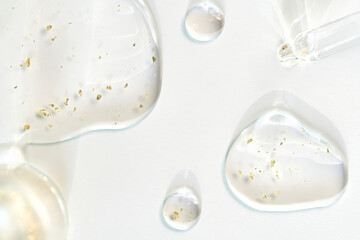 Transparent serum with gold flakes and droppers on white background for skincare and beauty concepts.