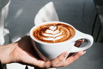 heart latte art, holding a mug of cocoa latte 