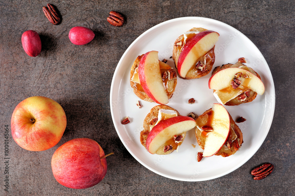 Poster plate of crostini appetizers with red apples, brie cheese and walnuts. top view table scene against 