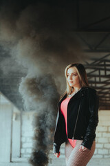 A woman in a red shirt stands in a dark room with a black jacket