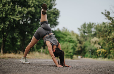 Fototapeta premium A young girl dances energetically in a park, showcasing joy and freedom. Her vibrant movements create a cheerful atmosphere amidst natural surroundings.