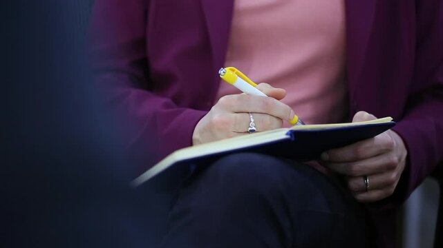 Person holding a pen writing in a notebook. focusing on the act of taking notes or jotting down thoughts, conveying concentration and productivity