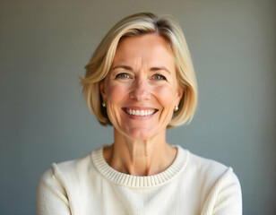 Fototapeta premium A smiling eldery woman Caucasian woman with short blonde hair wearing a cream-colored sweater