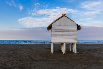 Wooden house with a thatched roof on piles on the shore of the Caspian Sea